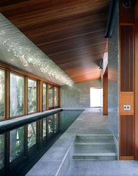 Photo by Catherine Tighe.  A shower with a translucent glass exterior wall and interior hinged glass doors (not installed at the time of the photo) is used for washing before entering the chlorine-free pool.   An electrified sliding pool cover can be used to maintain the water temperature and control the humidity when the pool is not in use.  Sliding doors to the vestibule have an operable transom to the second floor master bedroom roof deck.