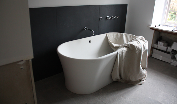 White resin tub with plaster-like finish against black Pennsylvania slate wainscot