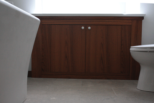 Teak storage cabinet inserted into wall under existing window
